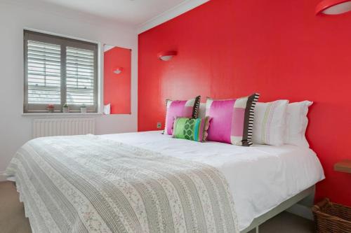 a bedroom with a red wall with a white bed at Stylish Apartment with Private Rooftop in Covent Garden in London
