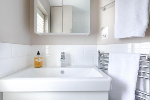 een witte badkamer met een wastafel en een spiegel bij Stylish Apartment with Private Rooftop in Covent Garden in Londen