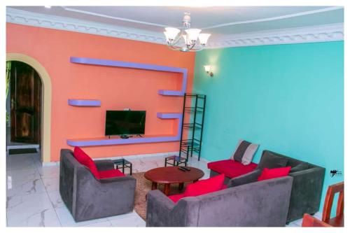 a living room with red chairs and a television at Résidences K and D in Bafoussam