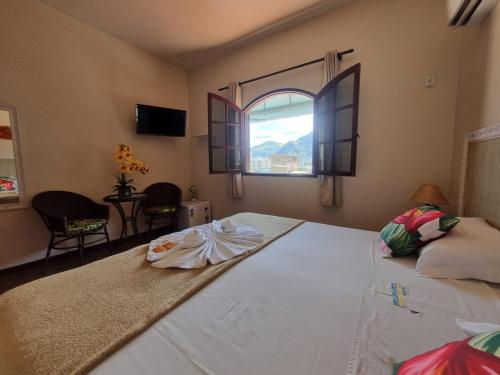 a bedroom with a large white bed with a window at Pousada Tuiuiu in Angra dos Reis