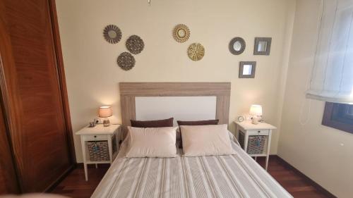 a bedroom with a bed with two tables and two clocks on the wall at Apartamento 1 dormitorio 4 personas en El Grove in O Grove