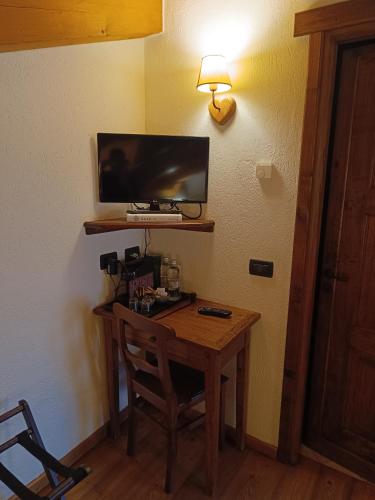a room with a wooden table with a television on a wall at Hotel Lo Campagnar in Courmayeur