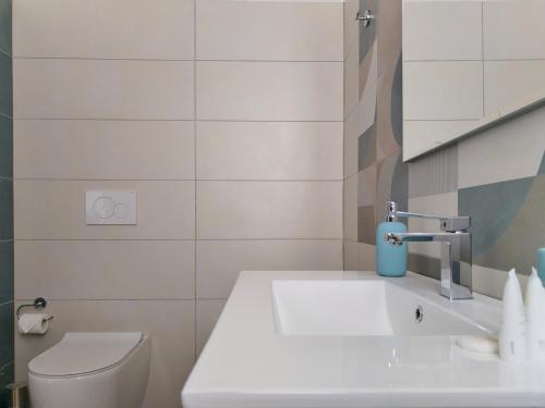 a white bathroom with a toilet and a sink at Villa Ina Lux in Fontane Bianche