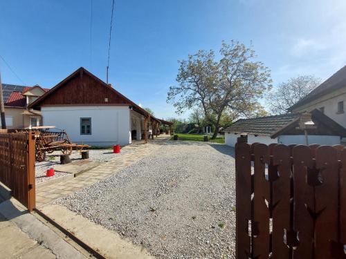 a driveway with a fence in front of a building at Trinity Vendégház Abádszalók in Abádszalók