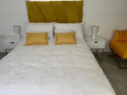 a bedroom with a white bed with two yellow pillows at Miami Gardens in Roodepoort