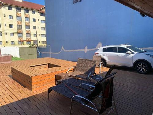 a deck with two chairs and a car parked on it at Casa com Piscina em Região Nobre de Cascavel in Cascavel