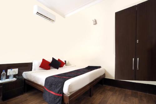 a bedroom with a bed with red and black pillows at TRP VIVEK CONTINENTAL in Gwalior