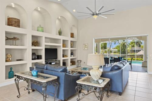 a living room with blue couches and tables at Cape Serenity- Luxury Waterfront Villa with Kayaks in Cape Coral