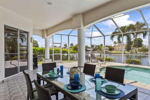 a dining room with a table and chairs and a pool at Cape Serenity- Premier Waterfront Villa with Kayaks and Bikes in Cape Coral