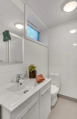 a white bathroom with a sink and a toilet at Cozy apartment with a view in Tromsø