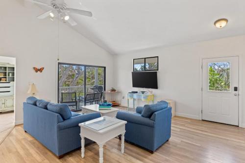 a living room with two blue couches and a tv at Captiva Beach Bungalow on Turner Beach in Captiva