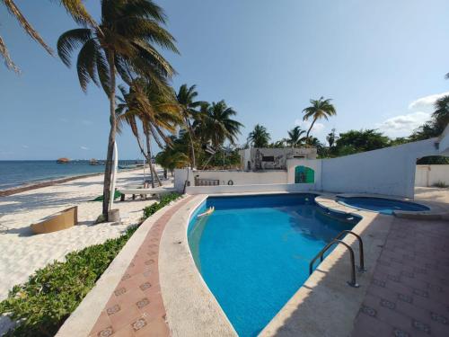 a swimming pool next to a beach with palm trees at ON THE BEACH SURFERS SUNRISE HAVEN 2 in Cancún
