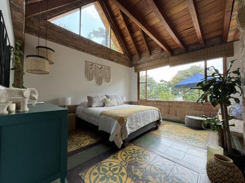 1 dormitorio con cama y ventana grande en Casa Kolibri, en Pacho
