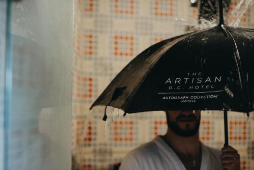 a man holding an umbrella in the rain at The Artisan D.C. Hotel, Autograph Collection in Bogotá