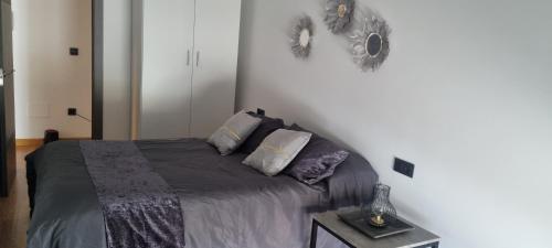 1 dormitorio con 1 cama con manta gris y almohadas en Apartamento tranquilo, en Ponferrada