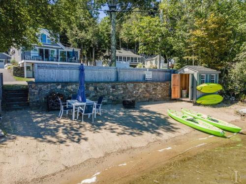 a patio with a table and chairs and kayaks on the beach at Beautiful Home 30 Feet from the Sand at Spofford Lake! in Chesterfield