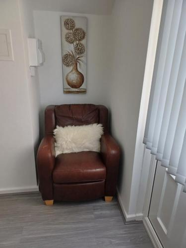 a brown chair with a white pillow in a room at Beautiful maisonette in Leeds