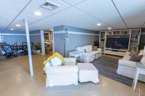 a living room with white furniture and a flat screen tv at Beautiful Home 30 Feet from the Sand at Spofford Lake! in Chesterfield