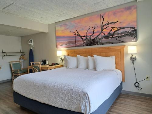 a hotel room with a bed and a painting on the wall at Days Inn & Suites by Wyndham Jekyll Island in Jekyll Island