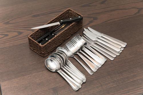 a group of silver forks and a knife next to a basket at ガジュマルの庭～itoman in Ō