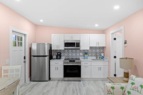 a kitchen with white cabinets and a stainless steel refrigerator at Charming Suite with Balcony and Bikes at Historic Sandpiper Inn in Sanibel