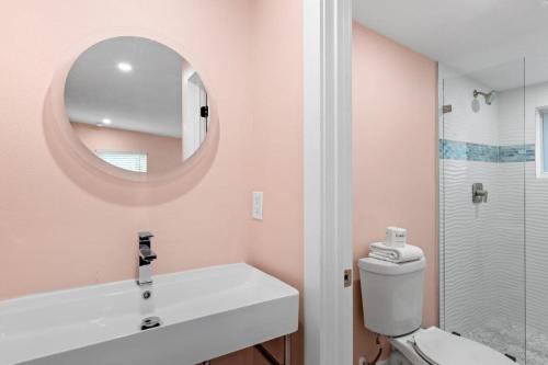 a bathroom with a toilet and a sink and a mirror at Charming Suite with Balcony and Bikes at Historic Sandpiper Inn in Sanibel