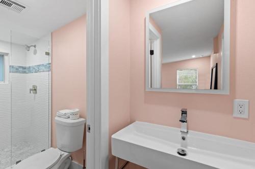 a bathroom with a toilet and a sink and a mirror at Charming Suite with Balcony and Bikes in Historic Sandpiper Inn in Sanibel