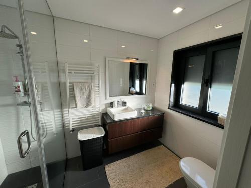 ein Bad mit einer Dusche, einem Waschbecken und einem Spiegel in der Unterkunft Pinheiros House by ALPONTE in Monção