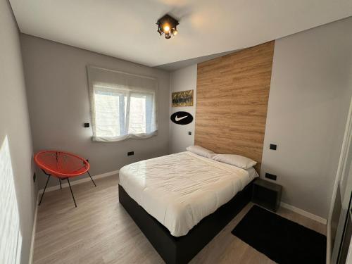 ein Schlafzimmer mit einem Bett und einem roten Stuhl in der Unterkunft Pinheiros House by ALPONTE in Monção