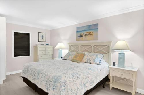 a white bedroom with a bed and two night stands at Family-Friendly Bayside Villa at South Seas Resort in Captiva