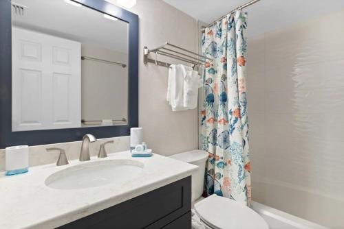 a bathroom with a sink and a toilet and a mirror at Family-Friendly Bayside Villa at South Seas Resort in Captiva