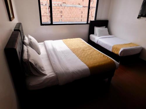 a bedroom with two beds and a window at Hotel Casa Navi in Bogotá