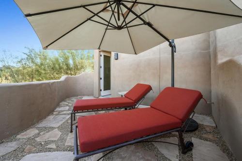 two red chairs and an umbrella on a porch at Serenity Peaks- Gorgeous Pet Friendly Villa in Scottsdale with Pool, Spa, and Bikes in Scottsdale