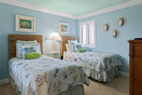 two beds in a bedroom with blue walls at Gorgeous Renovated Residence in Upscale Sanibel Harbour Tower in Fort Myers