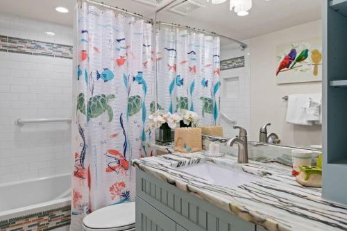 uma casa de banho com um lavatório, um WC e uma cortina de chuveiro. em Gorgeous Renovated Residence in Upscale Sanibel Harbour Tower em Fort Myers
