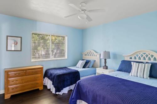 a blue bedroom with two beds and a ceiling fan at Cute Coastal Home with Pool in Fort Myers