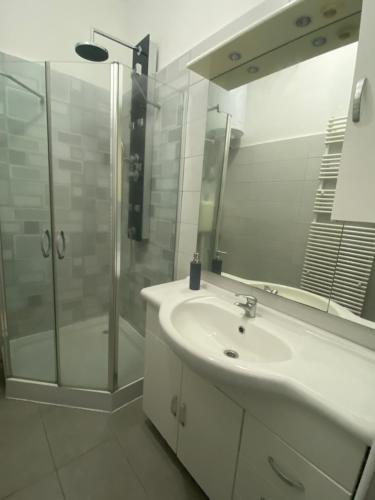 a white bathroom with a sink and a shower at Tündér Pension in Mogyoród