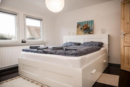 - un lit blanc dans une chambre avec 2 fenêtres dans l'établissement Stadt-Ferienwohnung mit 55 m² für 2 erw. Personen und Kind bis 3 Jahren, à Bad Lauterberg