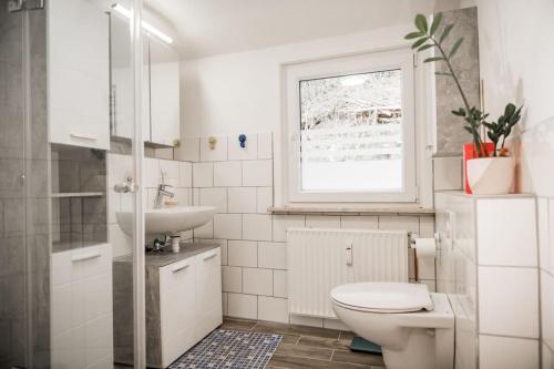 La salle de bains blanche est pourvue de toilettes et d'un lavabo. dans l'établissement Stadt-Ferienwohnung mit 55 m² für 2 erw. Personen und Kind bis 3 Jahren, à Bad Lauterberg