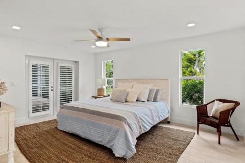 a bedroom with a bed and a chair and windows at Sanibel Serenity- NEW Gorgeous Near Beach Villa with Pool in Sanibel