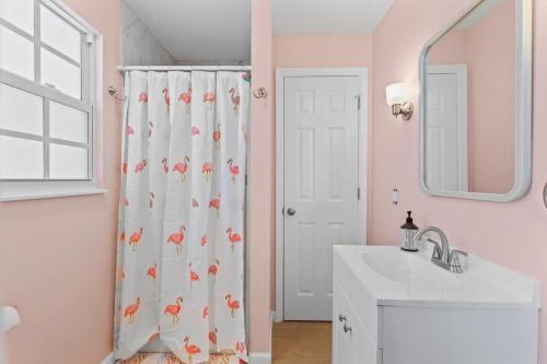 a bathroom with a shower curtain with a sink and a mirror at Gorgeous Apartment on Mango St Steps to Beach in Fort Myers Beach