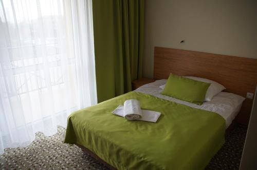 a bedroom with a green bed with a hat on it at Hotel ***NAT Sarbinowo in Sarbinowo