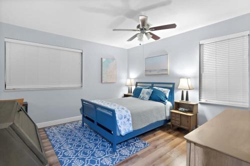a bedroom with a blue bed and a ceiling fan at Colonel's Cottage- Sanibel Beach Retreat Fantastic Amenities in Sanibel