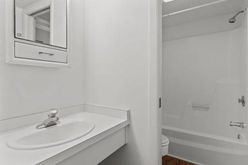 a white bathroom with a sink and a mirror at Comfy Waterfront Condo at Tennisplace Sanibel in Sanibel