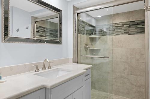 a white bathroom with a sink and a shower at Loggerhead 253- Beachfront Residence w Vaulted Ceilings in Sanibel