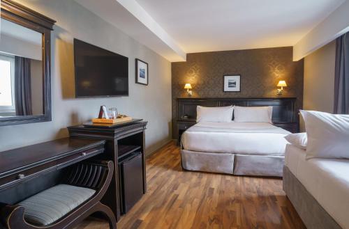 Habitación de hotel con cama, escritorio y TV. en Lennox Ushuaia en Ushuaia