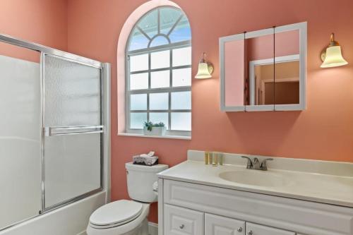 a bathroom with a toilet and a sink and a mirror at Mango Margarita- Beach Home with Pool Sleeps 12 in Fort Myers Beach