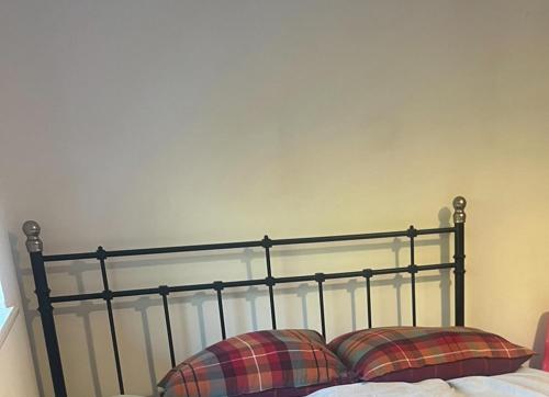 a metal bed with two plaid pillows on it at double room in New Barnet