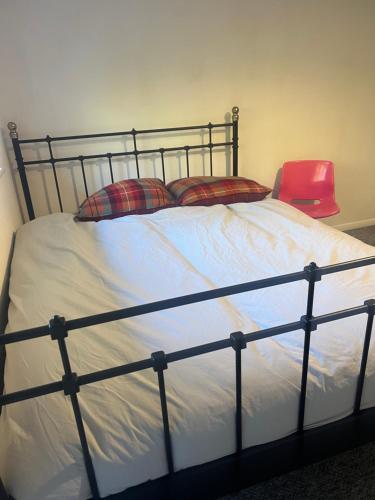 a bed with two pillows and a red chair at double room in New Barnet