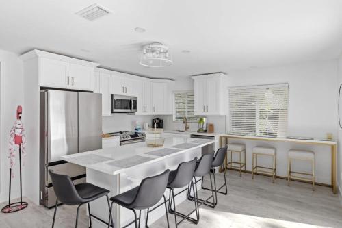 a white kitchen with a large white island with chairs at Stunning Near Beach Residence on Palermo Circle in Fort Myers Beach